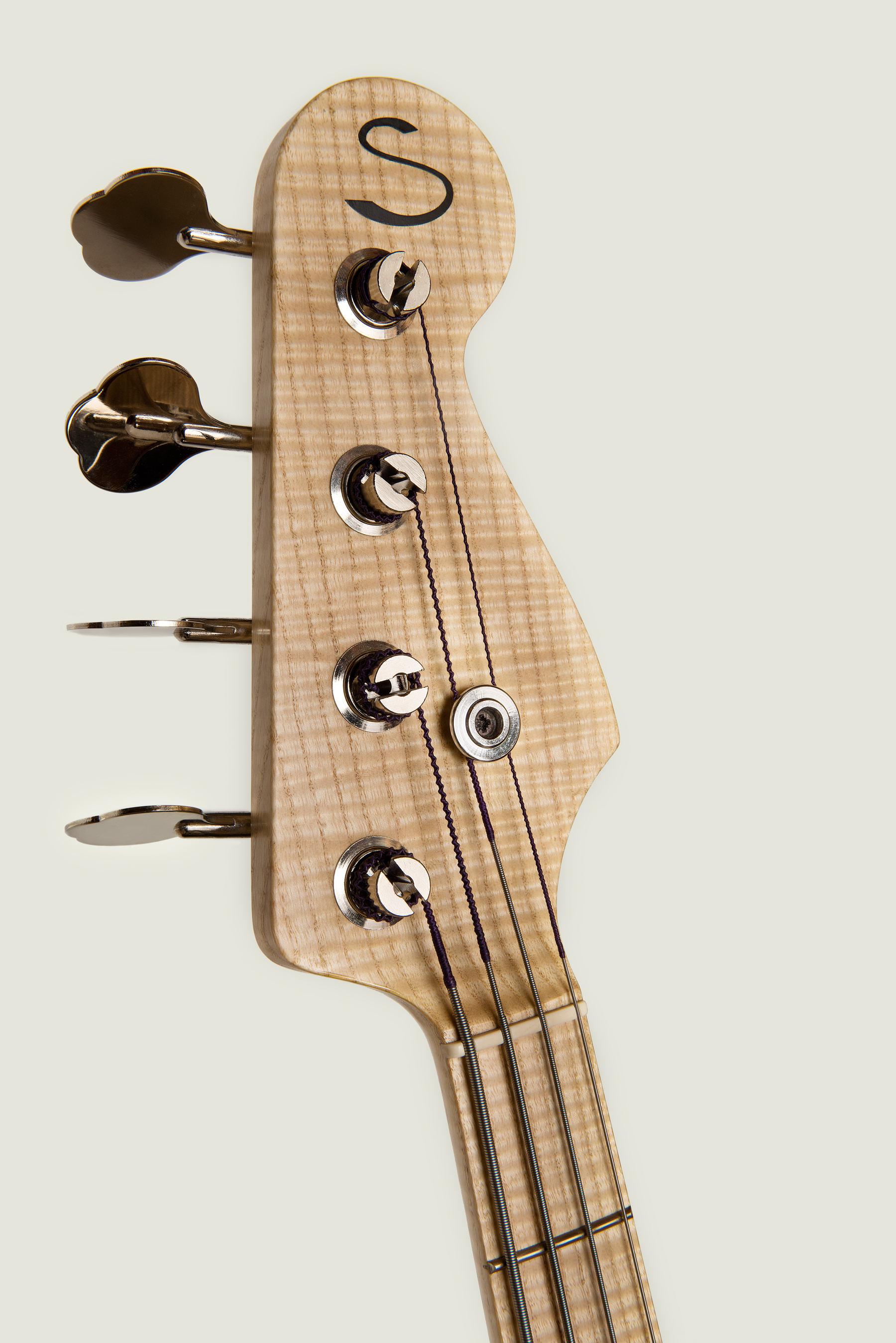 Guitar Maker Peter Stephen uses a string button to pull the strings down for the correct angle and tension for the strings on an electric bass guitar
